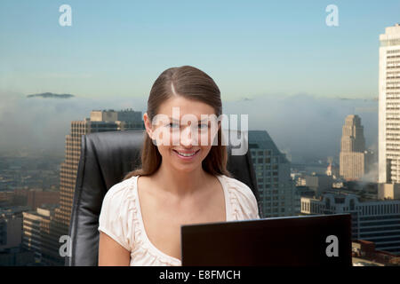 Portrait of young businesswoman in office with office buildings in background Stock Photo