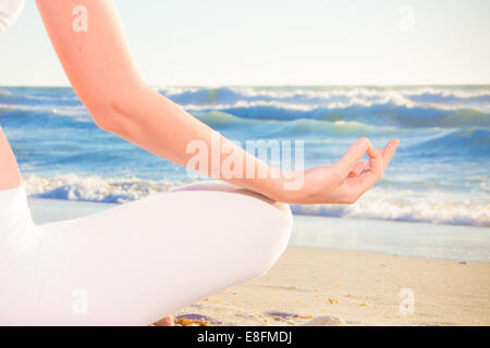 Woman practicing yoga on beach Stock Photo