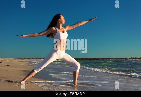 Woman practicing warrior 2 yoga pose on beach Stock Photo