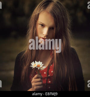 Portrait of a teenage girl holding a small bunch of daisies, Poland