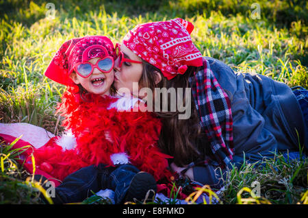 Woman sitting in a meadow kissing her daughter, Texas, USA