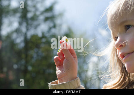 Portrait of a girl holding daisy flower