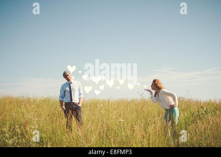 Woman standing in a meadow blowing hearts to her boyfriend, Nashville, Tennessee, USA Stock Photo