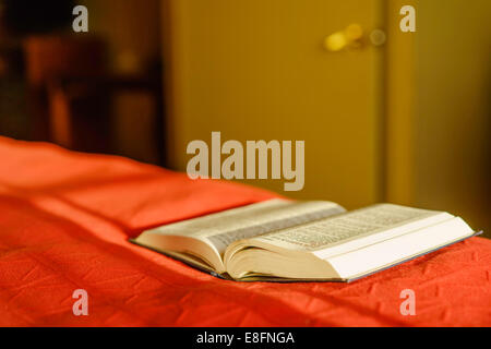 Open Bible lying on the edge of a bed Stock Photo