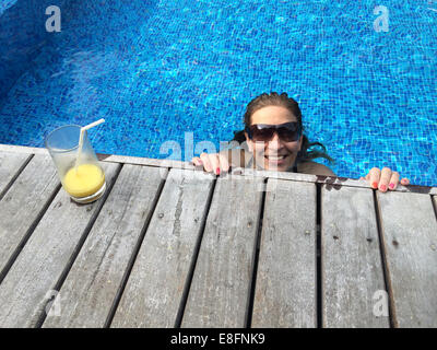 Woman with cocktail relaxing in swimming pool Stock Photo
