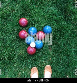Bocce balls on green grass in park with woman's shoes Stock Photo