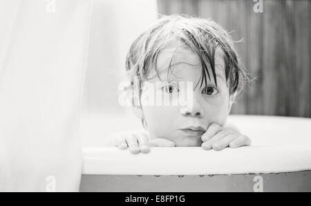 Portrait of a boy looking over edge of a bathtub Stock Photo