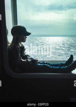 Side view of boy sitting in  window on ferry