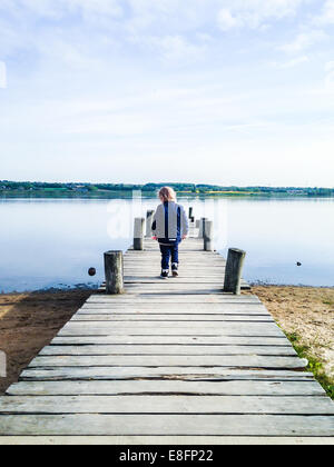 Rear view of  boy standing on  wooden jetty Stock Photo