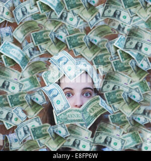 Portrait of a woman buried in American dollar bills Stock Photo