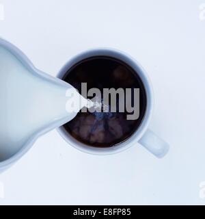 Overhead view of milk being poured into cup of coffee Stock Photo