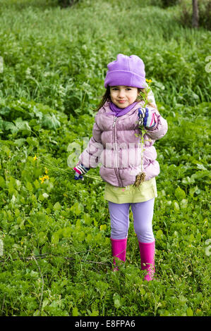 Portrait of little girl (4-5) holding wildflowers outdoors Stock Photo