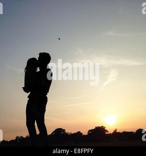 Silhouette of father and daughter standing in rural landscape Stock Photo