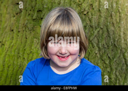 Portrait of girl in front of oak tree trunk with bark Stock Photo