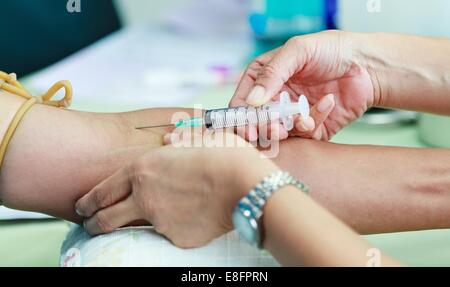 Doctor drawing blood sample from arm for blood test Stock Photo