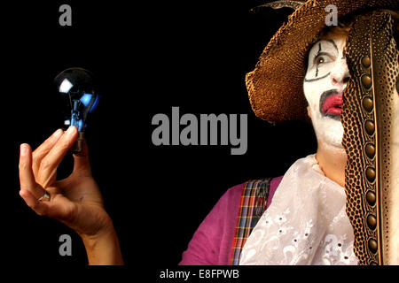 Female Clown holding a light bulb and feather Stock Photo