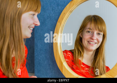 Portrait of caucasian redhead girl looking in mirror Stock Photo