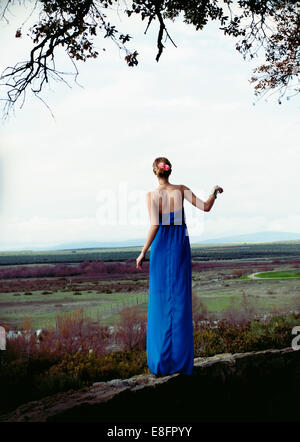 Woman wearing blue long dress standing on stone wall Stock Photo