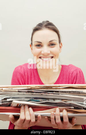 Young woman holding a stack of newspapers Stock Photo