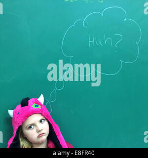 Portrait of a Girl standing in front of blackboard with puzzled expression Stock Photo
