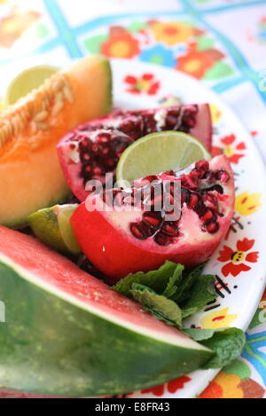 Plate full of summer fruits including melons and pomegranate on vintage plate