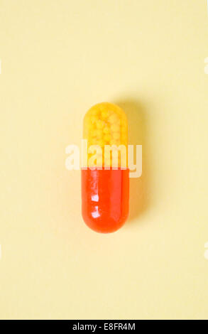 Red and yellow capsule on pale yellow background Stock Photo