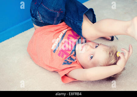 Boy on floor upside down playing with toys Stock Photo