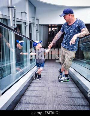 Father and son standing on a travelator Stock Photo