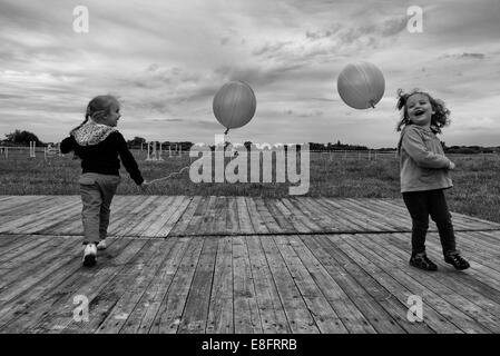 Two girls playing outdoors with balloons Stock Photo