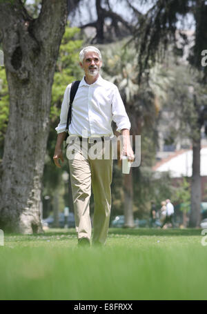 Businessman walking through park Stock Photo