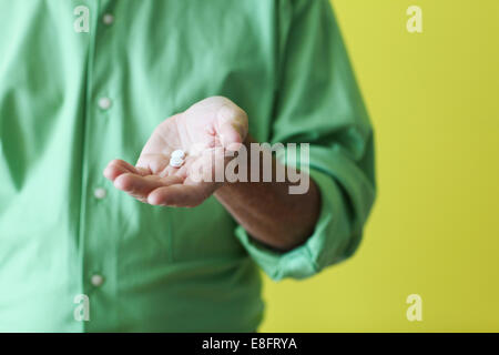 Man holding pills in palm of his hand Stock Photo