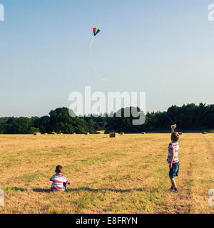Two boys in a field flying a kite, England, UK Stock Photo