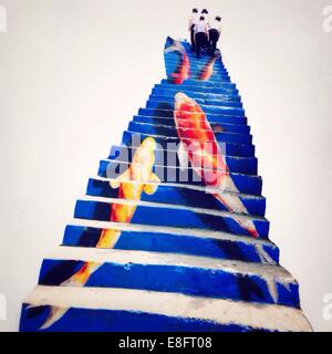 Four men walking up karp koi painted staircase Stock Photo