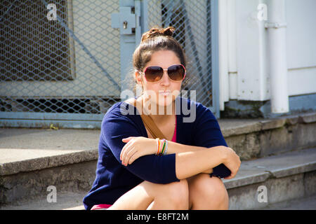 Woman wearing sunglasses sitting on a step Stock Photo
