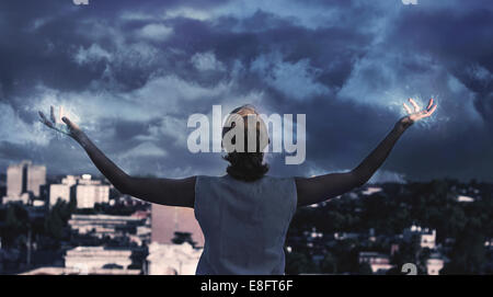 Rear view of a woman holding her arms out to a stormy sky, Argentina Stock Photo