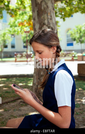 Teenage schoolgirl using mobile phone outside school building Stock Photo