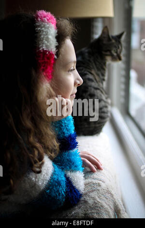 Girl and cat looking out of window Stock Photo