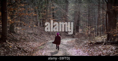 Girl walking along footpath through forest Stock Photo