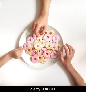 Girl's hands reaching for biscuits from plate Stock Photo