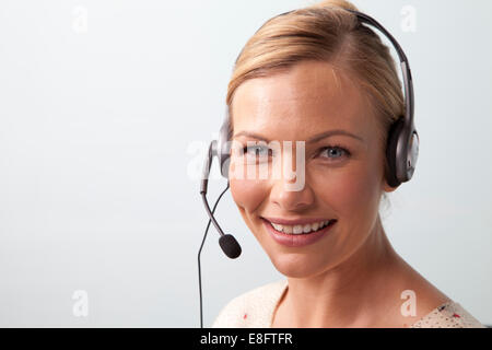 Smiling woman talking on the phone using a telephone headset Stock Photo