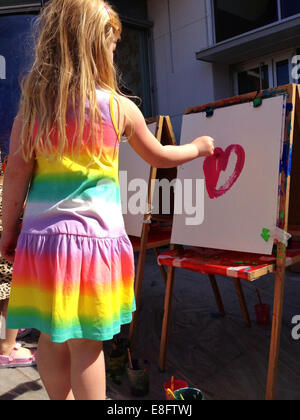 Rear view of a Girl standing in the garden painting a heart, Sweden Stock Photo