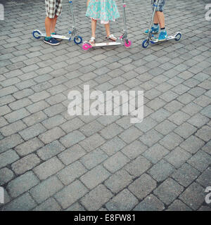 Close up of three children standing with their push scooters Stock Photo