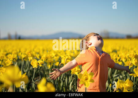 Carefree boy running through a daffodil field, USA