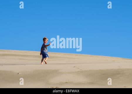 Boy running on beach looking over his shoulder Stock Photo