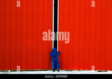 Boy looking through gap in a barn door, USA Stock Photo