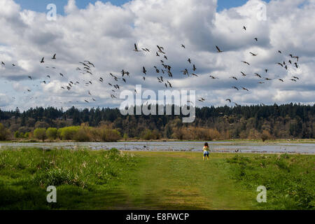 Girl looking at flock of birds (2-3 years) Stock Photo