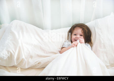 Happy girl snuggled up in bed Stock Photo