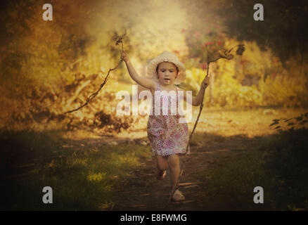 Girl running in a park carrying sticks Stock Photo