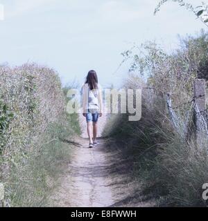 Rear view of girl walking along footpath Stock Photo