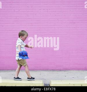 Boy walking on raised sidewalk Stock Photo
